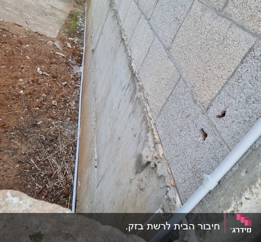 צינור פלסטיק לבן מחובר לקיר בטון